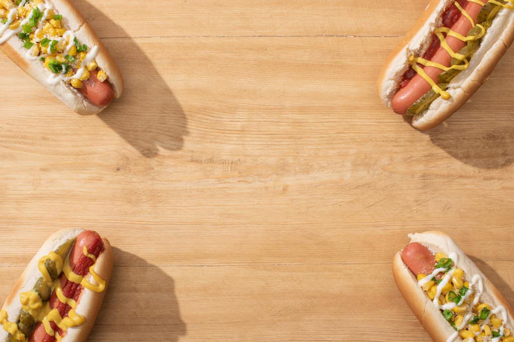 vista dall'alto di deliziosi hot dog con mais, cipolla verde e sottaceti sul tavolo di legno
 - Foto, immagini