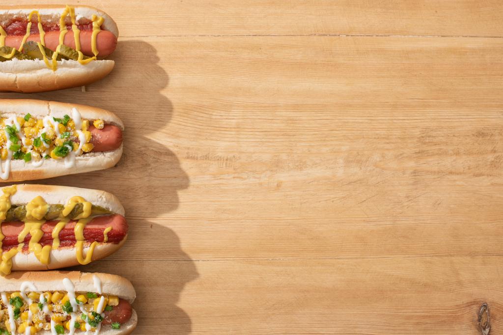 widok z góry pyszne hot dogi z kukurydzą, zielonej cebuli i ogórków na drewnianym stole - Zdjęcie, obraz