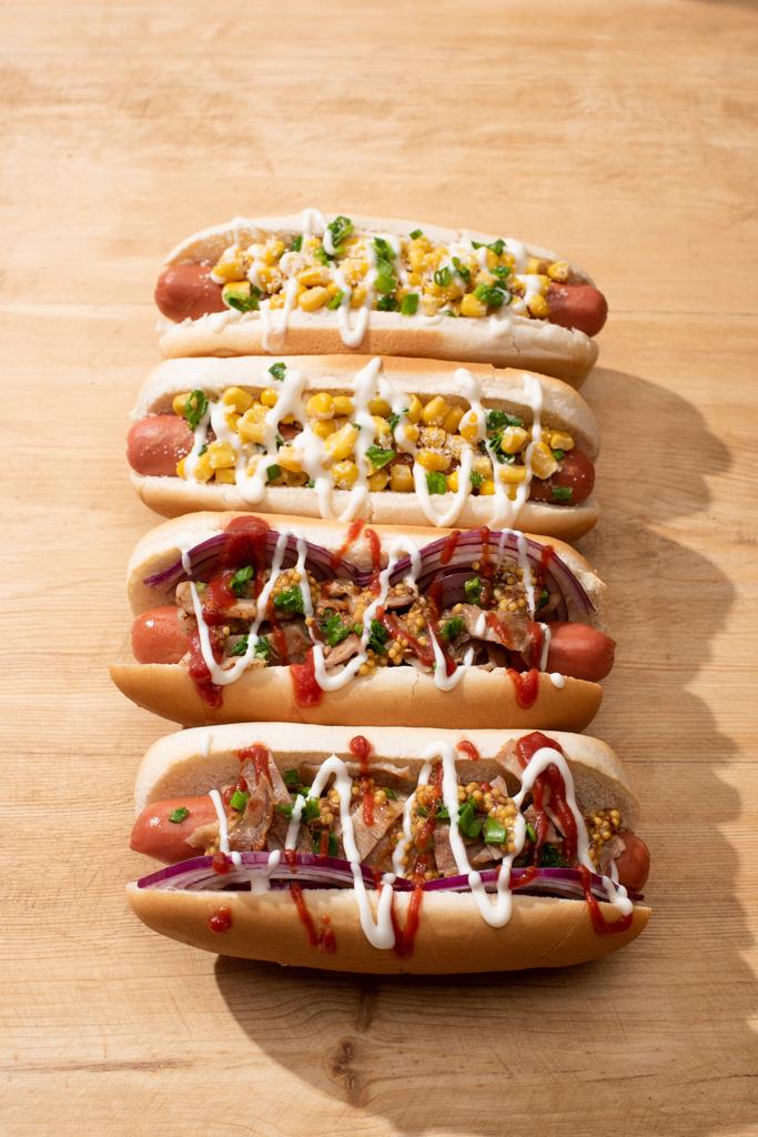 delicious hot dogs with red onion, bacon and corn on wooden table - Photo, Image