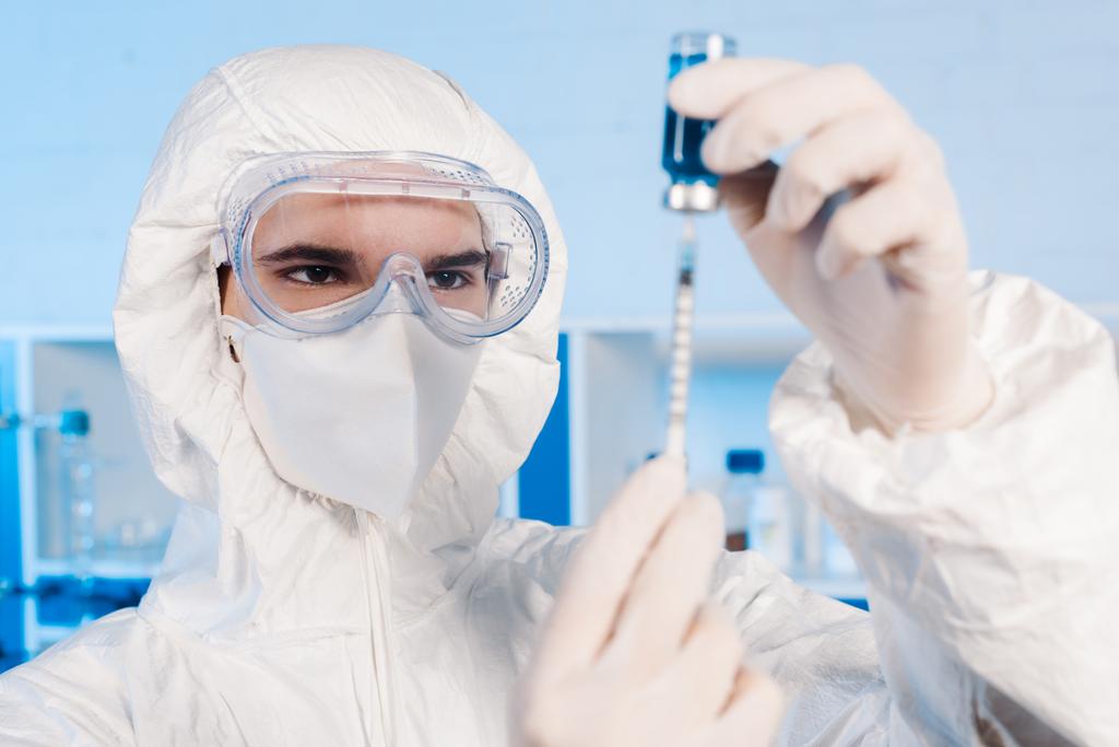 ラテックス手袋の科学者が注射器とワクチンで瓶を持ち  - 写真・画像