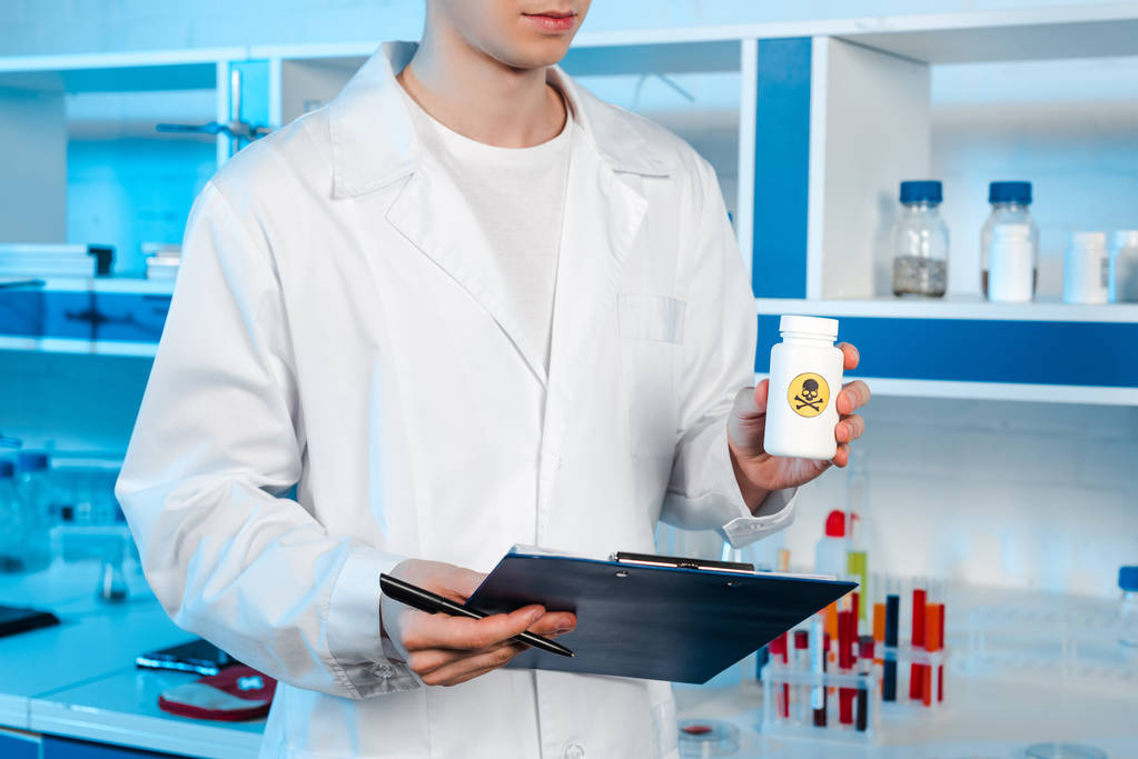 обрезанный вид ученого, держащего планшет и бутылку с токсичным символом
  - Фото, изображение