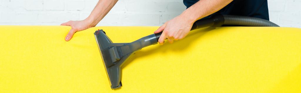 panoramic shot of cleaner removing dust on sofa with vacuum cleaner  - Photo, Image