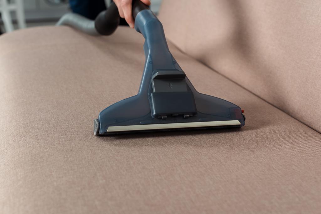 vue recadrée de l'homme nettoyage à sec canapé moderne avec aspirateur
  - Photo, image
