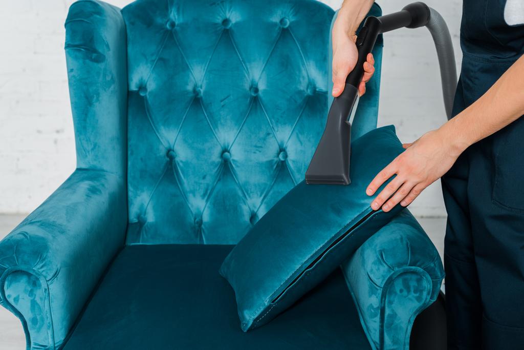 καλλιεργημένη άποψη του καθαριστικού μαξιλαριού στεγνού καθαρισμού σε μοντέρνα πολυθρόνα με ηλεκτρική σκούπα  - Φωτογραφία, εικόνα