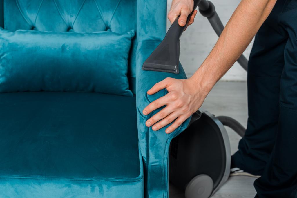 vista recortada de hombre limpieza en seco moderno sillón con aspiradora
  - Foto, imagen