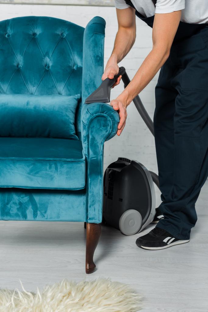 vista recortada de limpiador en uniforme lavado en seco moderno sillón con aspiradora
  - Foto, imagen