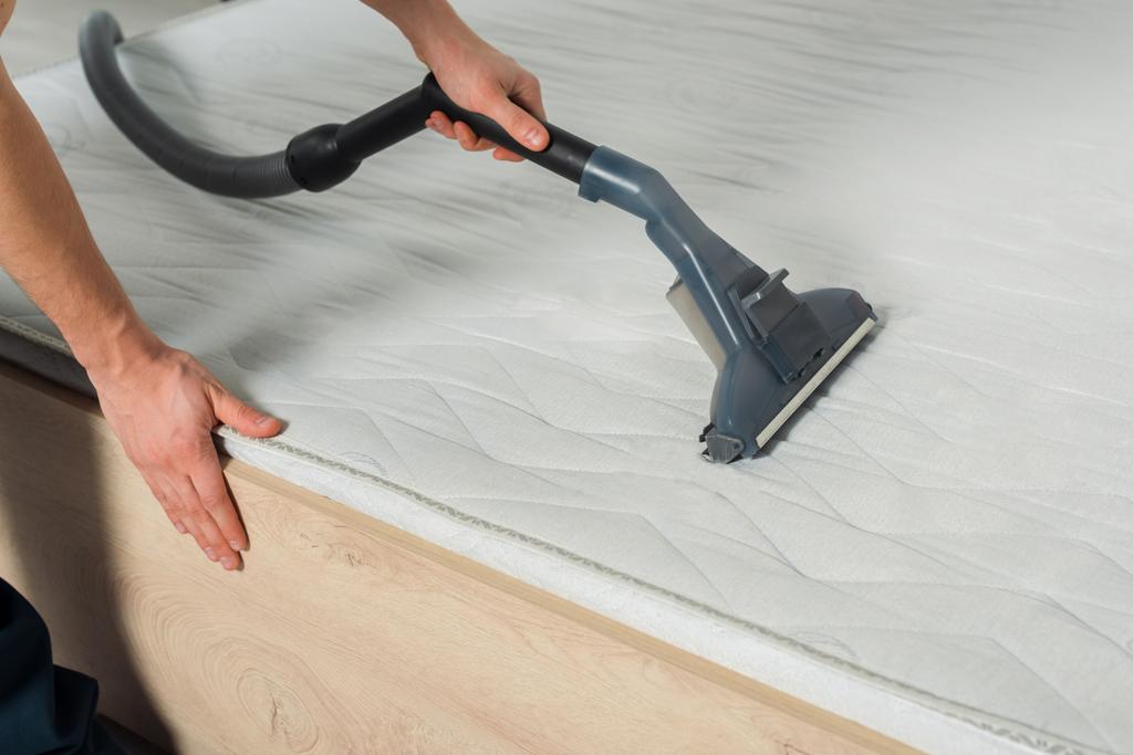 vista recortada de la limpiadora eliminar el polvo en el colchón con aspiradora
  - Foto, Imagen