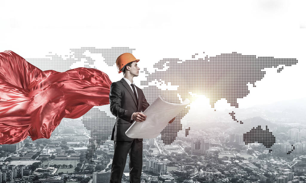 Confident engineer man in helmet and red cape against modern cityscape background - Photo, Image