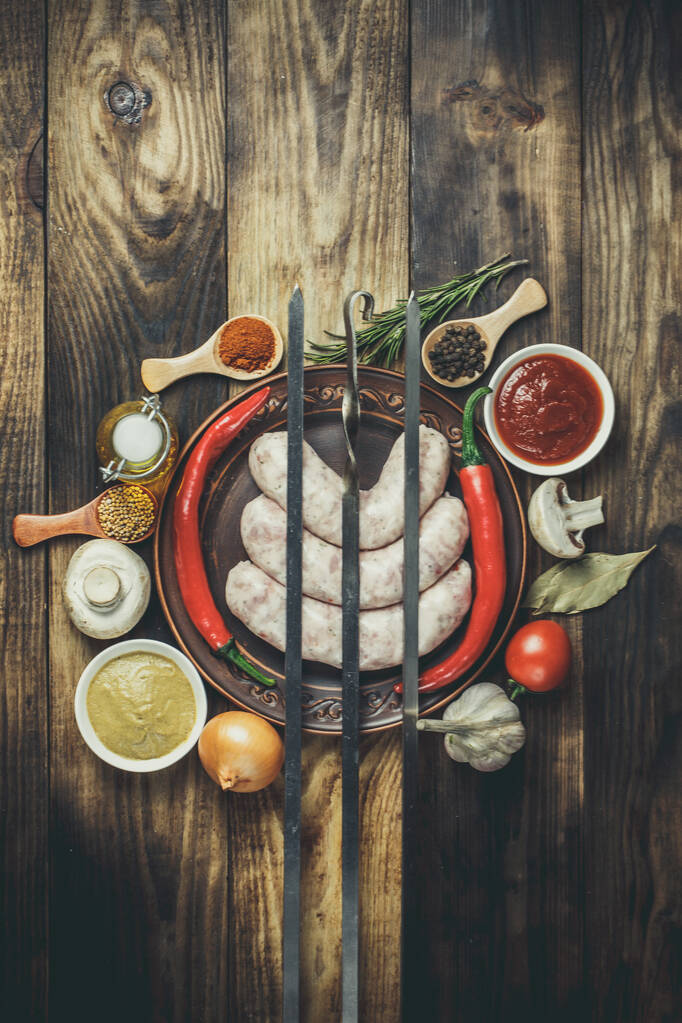Багато різних спецій, овочів та інгредієнтів, а також свіжі сирі ковбаски для барбекю для сім'ї
. - Фото, зображення