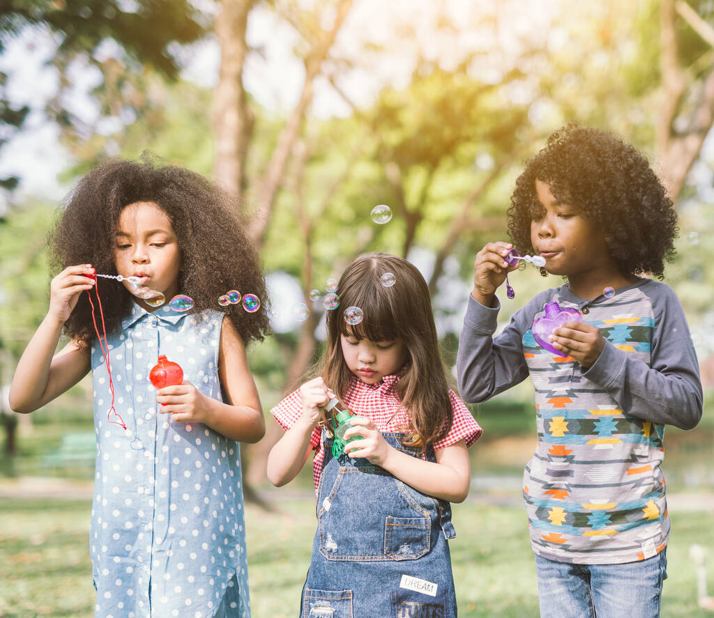Ryhmä Monipuolinen Lapset söpö ystäviä ottaa kupla hauskaa vihreä nurmikko puistossa
 - Valokuva, kuva