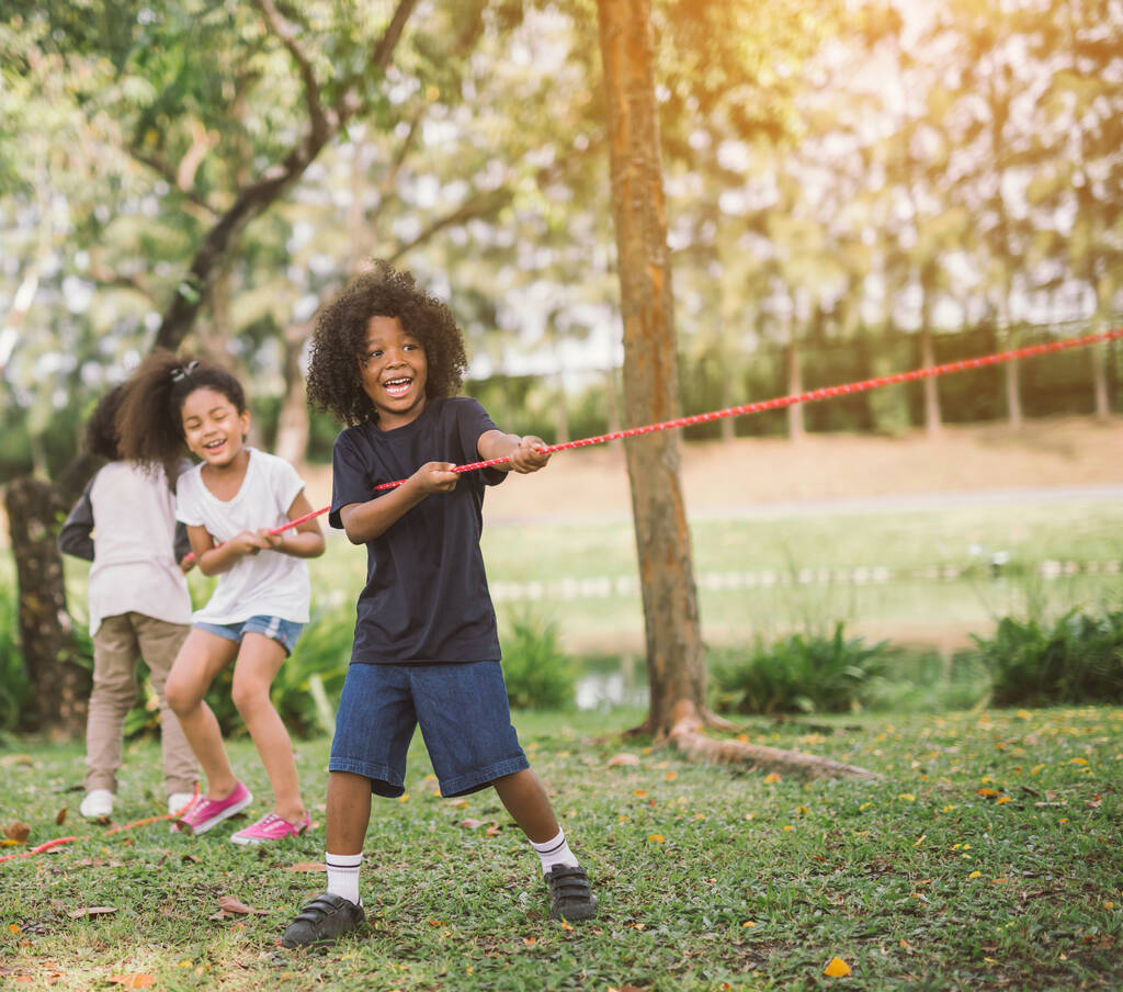 Niños felices jugando tirón de la guerra en el parque - Foto, Imagen