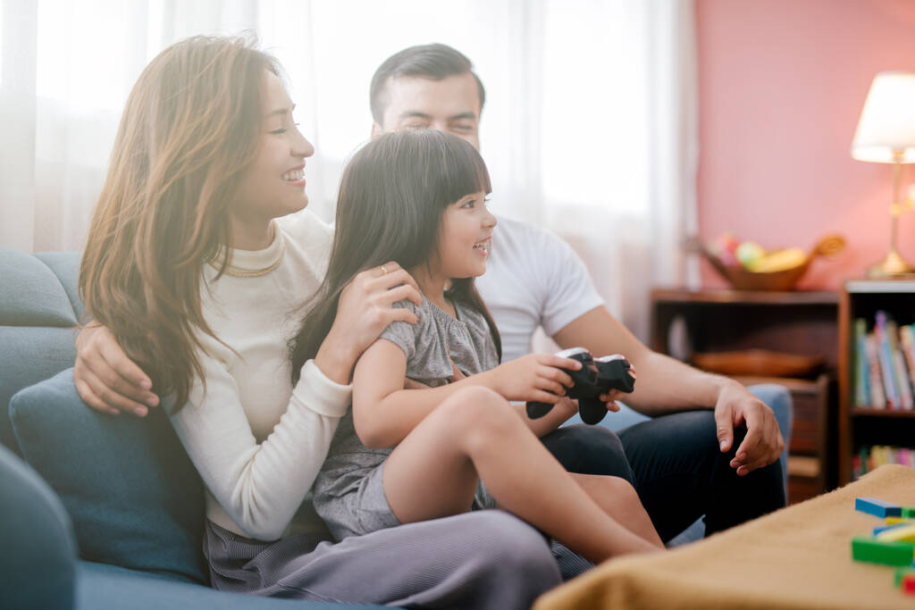 kleines Mädchen und Eltern spielen Videospiel zu Hause - Foto, Bild