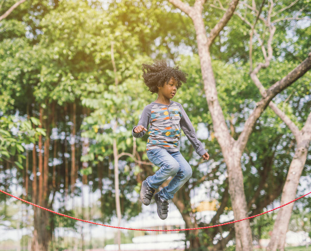αγόρι πηδάει πάνω από το σχοινί στο πάρκο την ηλιόλουστη καλοκαιρινή μέρα - Φωτογραφία, εικόνα