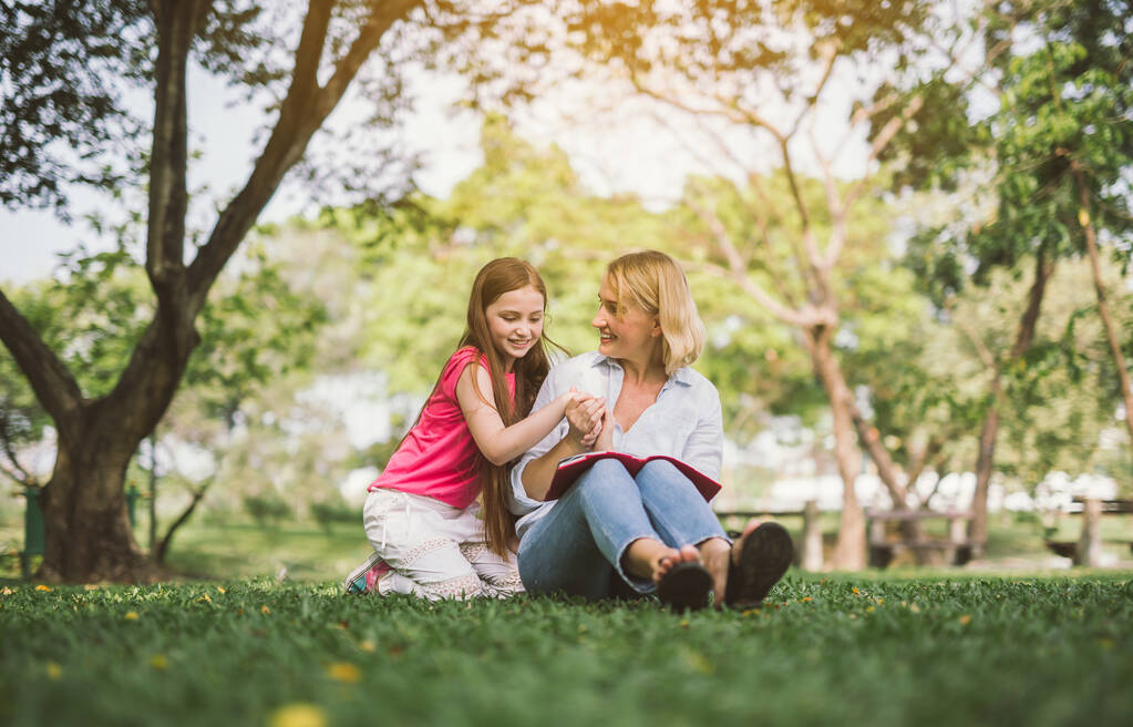 mom and daughter reading book in park - Photo, Image