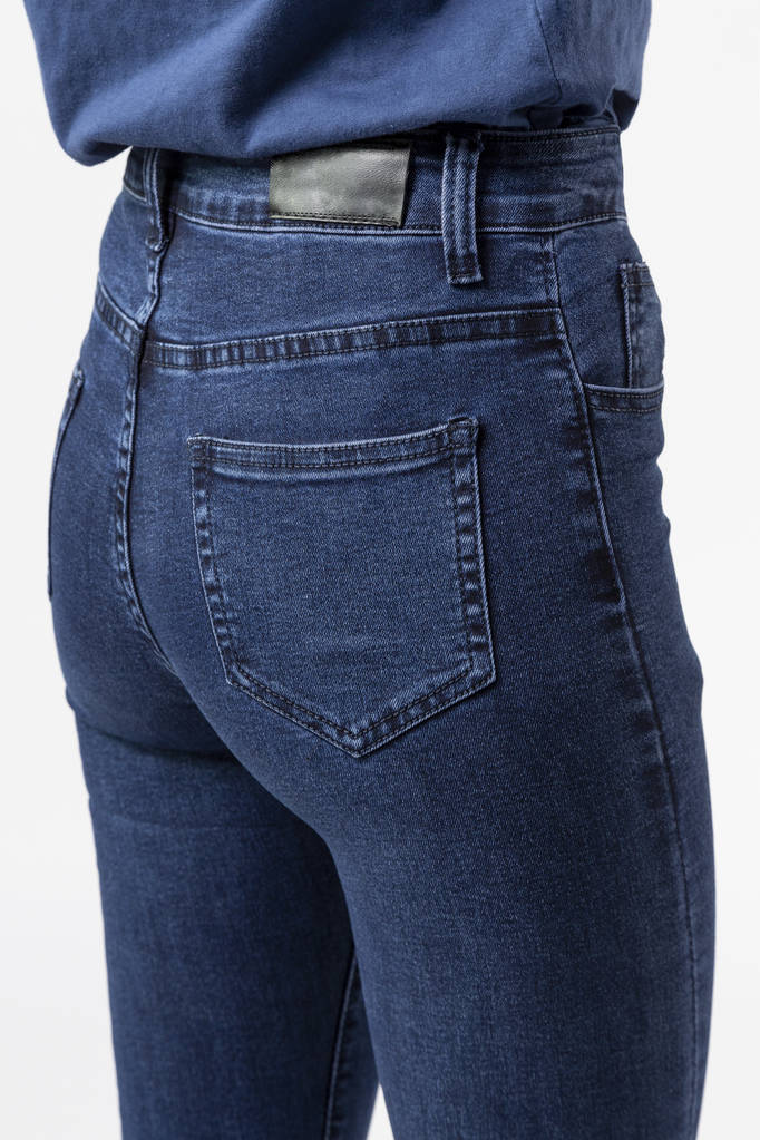 chica en jeans muestra pantalones vaqueros en fondo blanco de cerca, pantalones vaqueros azules - Foto, imagen