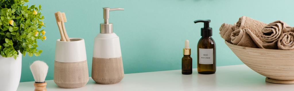 Панорамний вид на вазони, косметичні та гігієнічні засоби біля миски з рушниками у ванній кімнаті, концепція нульових відходів
  - Фото, зображення