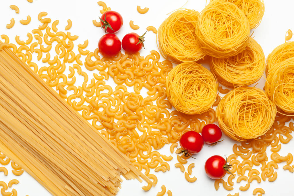 Pasta Spaghetti mit Zutaten zum Kochen von Pasta auf weißem Hintergrund, Ansicht von oben. - Foto, Bild