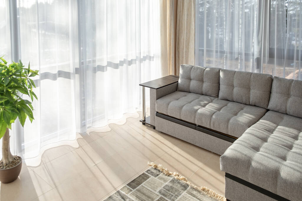 Nowoczesne wnętrze z dużą sofą i dużymi oknami. Poranne światło słoneczne z okien - Obraz - Zdjęcie, obraz