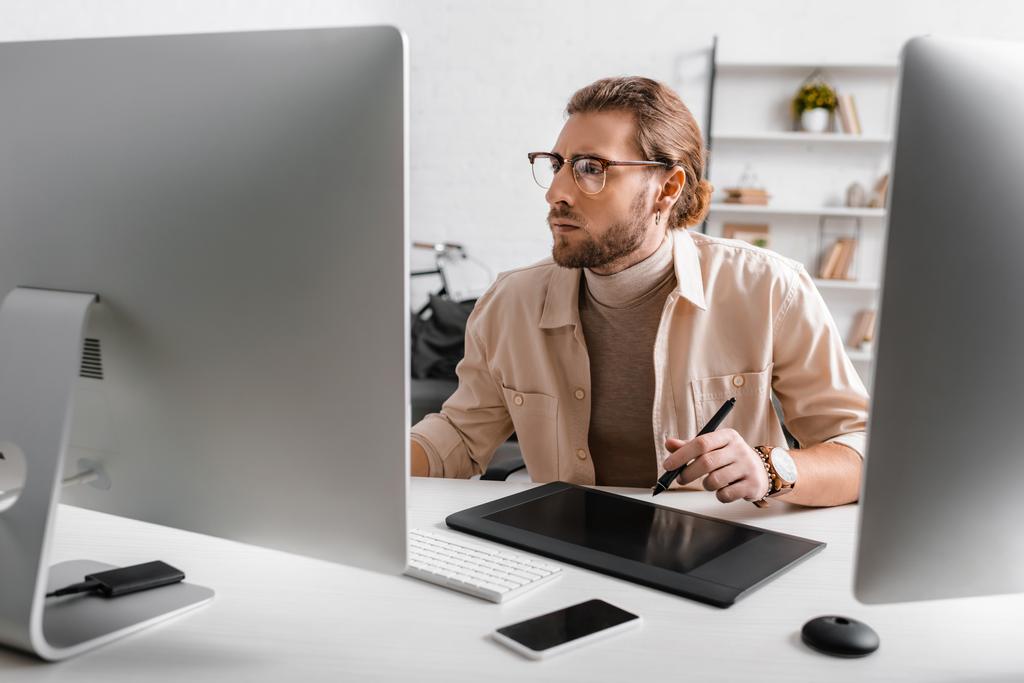 Przystojny artysta 3D za pomocą tabletu graficznego i komputerów przy stole w biurze  - Zdjęcie, obraz