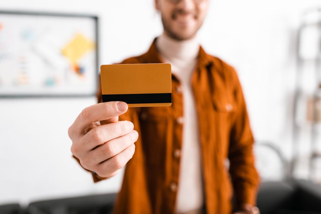 Выборочный фокус улыбающегося цифрового дизайнера, держащего кредитную карту в офисе
  - Фото, изображение