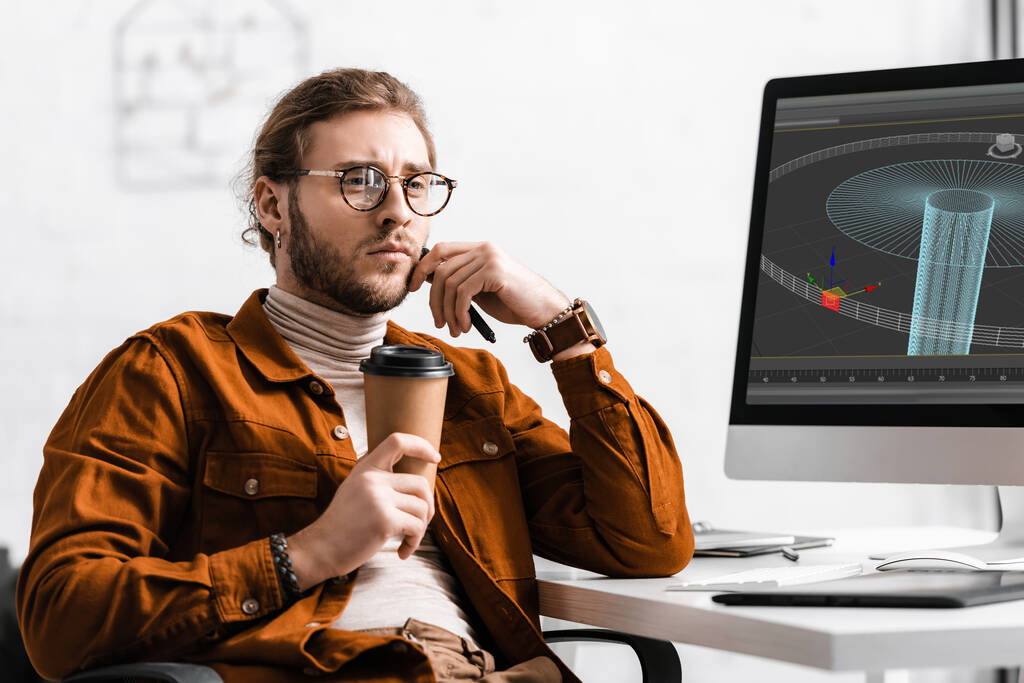 Umfassender digitaler Designer mit Coffee to go und Stift in der Nähe eines 3D-Projektes auf einem Computermonitor auf dem Tisch  - Foto, Bild
