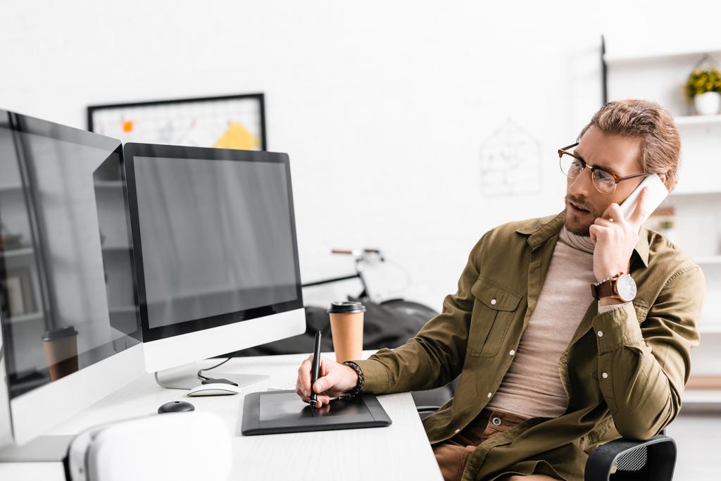 3d художник говорить на смартфоне и с помощью графики планшета и компьютеров за столом в офисе
  - Фото, изображение