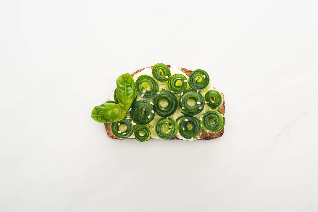 vista dall'alto del pane tostato fresco al cetriolo con foglie di basilico su sfondo bianco
 - Foto, immagini