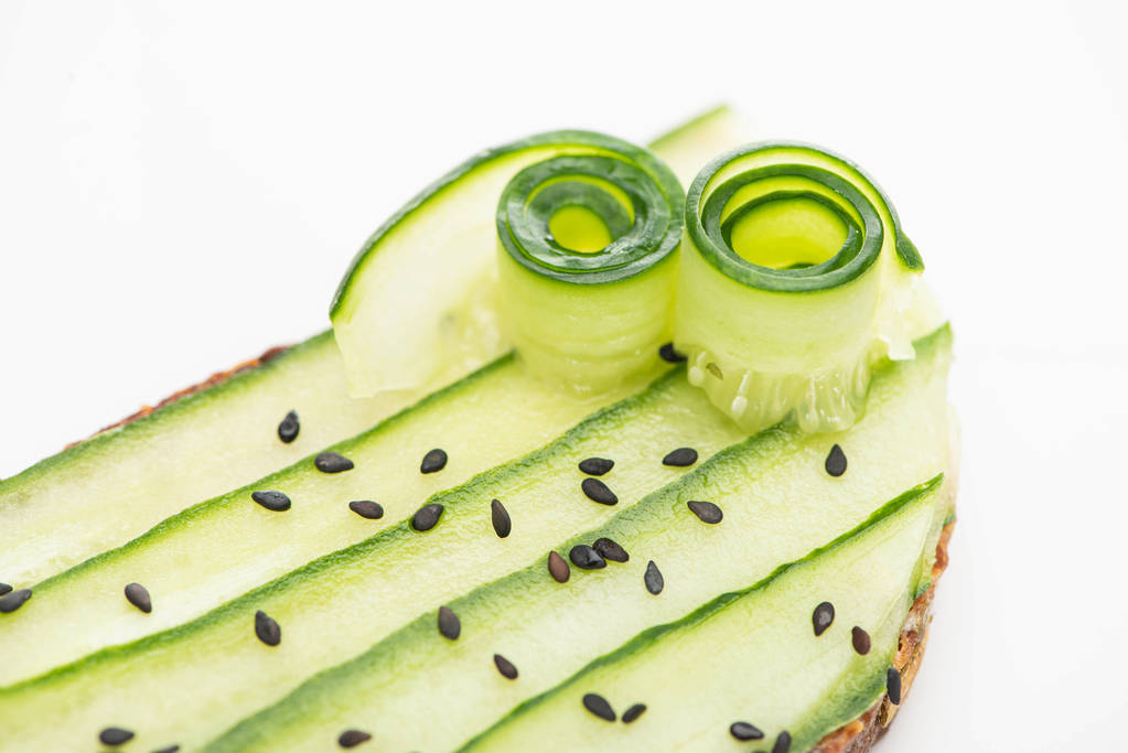 close-up zicht op verse komkommer toast met zaden geïsoleerd op wit - Foto, afbeelding
