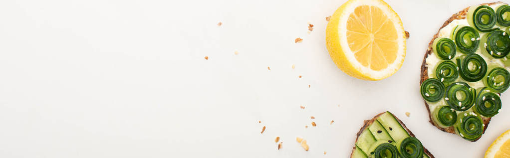 Draufsicht auf frische Gurken-Toasts mit Samen in Zitronennähe auf weißem Hintergrund, Panoramaaufnahme - Foto, Bild