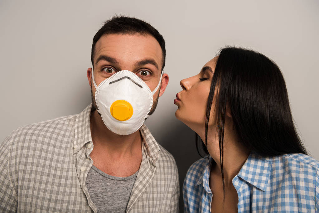 жінка цілує щасливого працівника в масці безпеки на сірому
   - Фото, зображення