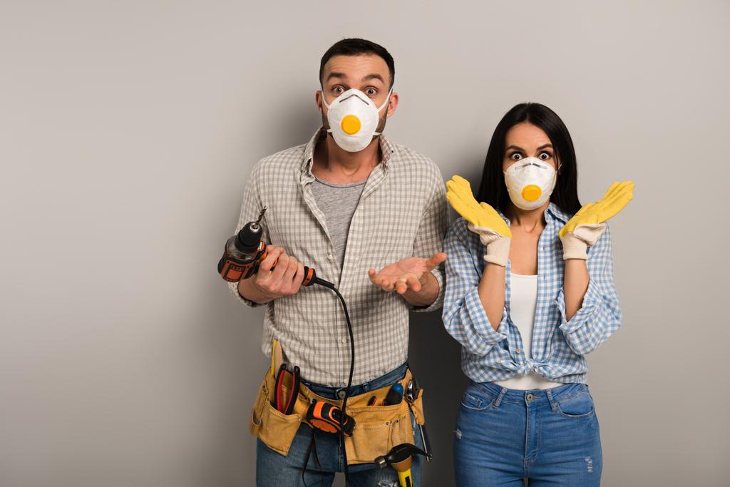 trabalhadores manuais assustados em máscaras de segurança segurando broca elétrica em cinza
  - Foto, Imagem