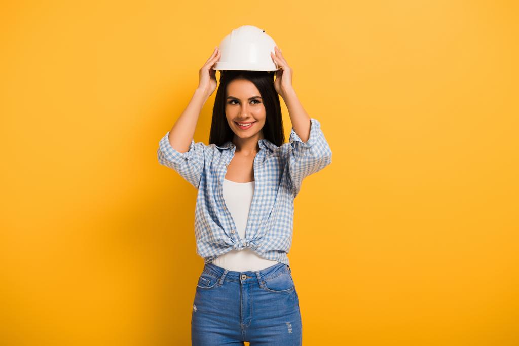 krásná usměvavá žena manuální pracovník nosí helmu na žluté  - Fotografie, Obrázek