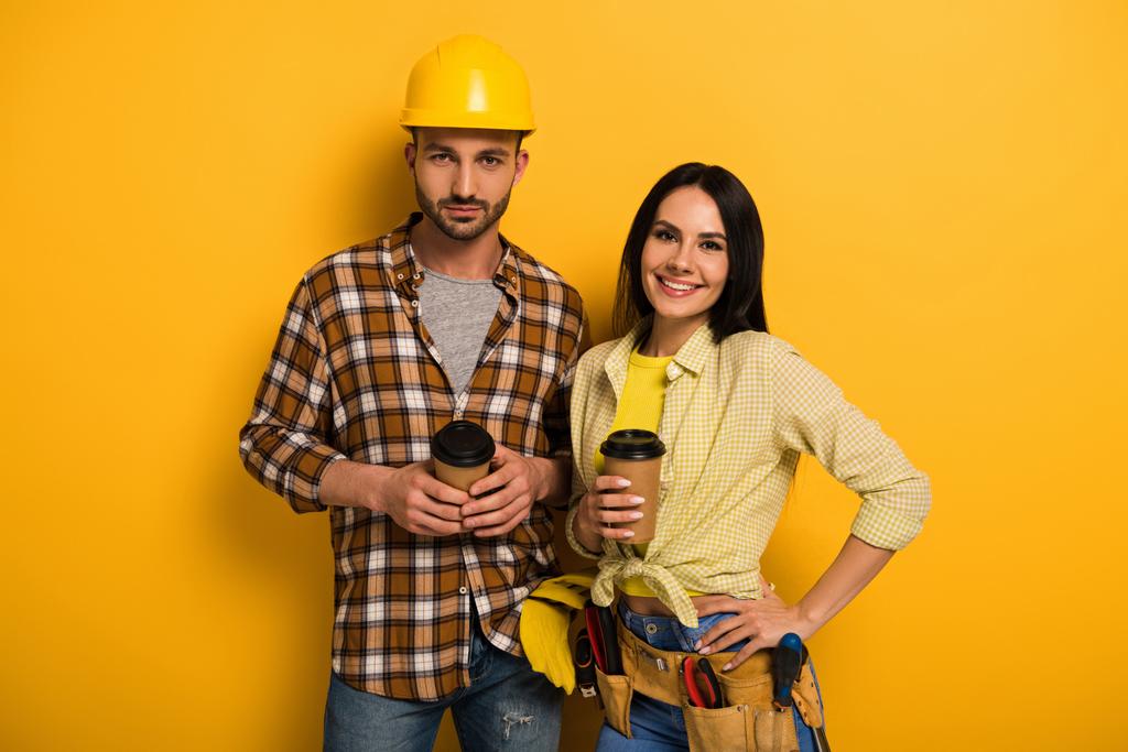 Профессиональные улыбающиеся рабочие, держащие кофе, чтобы перейти на желтый
      - Фото, изображение