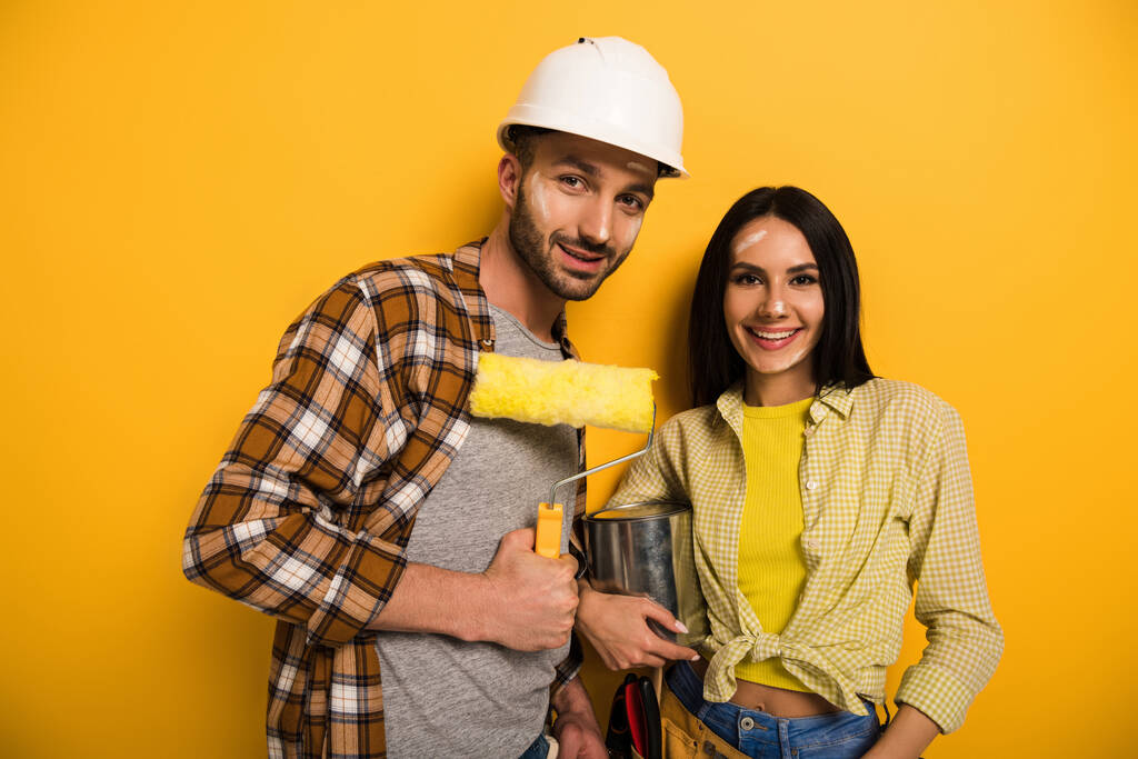 trabalhadores manuais sorridentes com rolo de pintura e lata de tinta no amarelo
   - Foto, Imagem