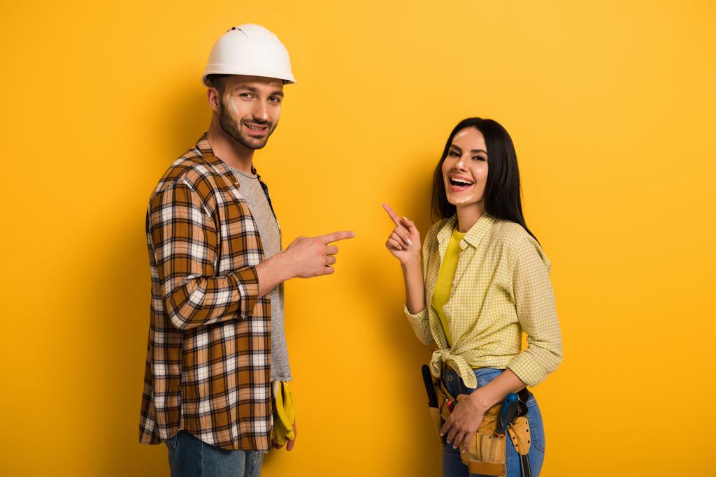 trabajadores manuales riendo señalándose unos a otros en amarillo
   - Foto, Imagen
