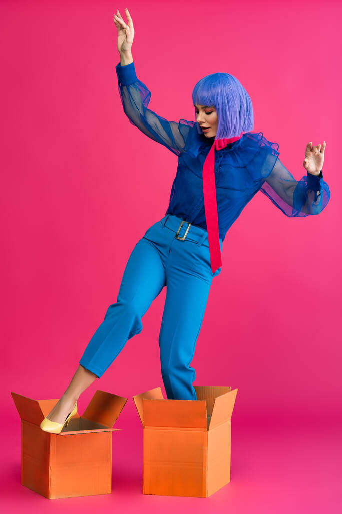 beautiful girl in purple wig standing in cardboard boxes on pink - Photo, Image