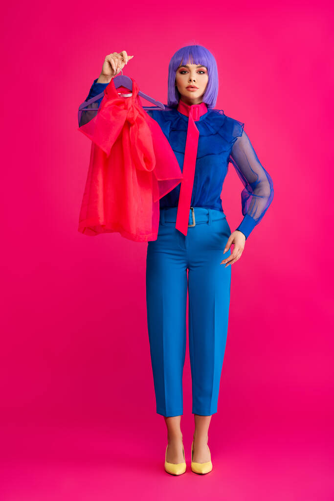 pop art dívka v fialové paruce drží věšák s červenou halenkou, na růžové  - Fotografie, Obrázek