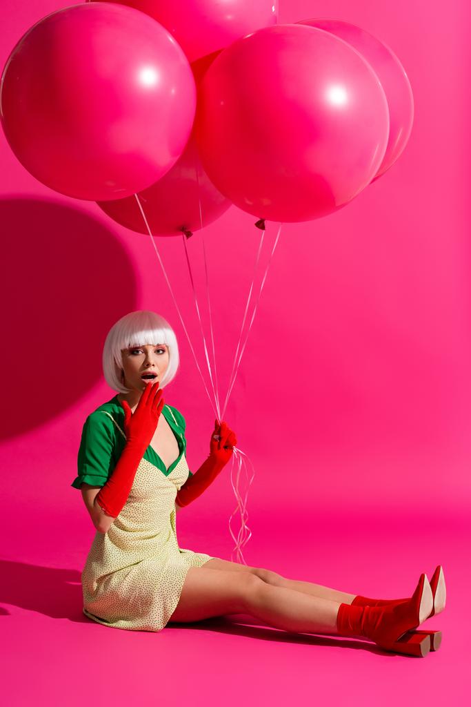 wstrząśnięty modne dziewczyna w białej peruce gospodarstwa balony na różowy  - Zdjęcie, obraz