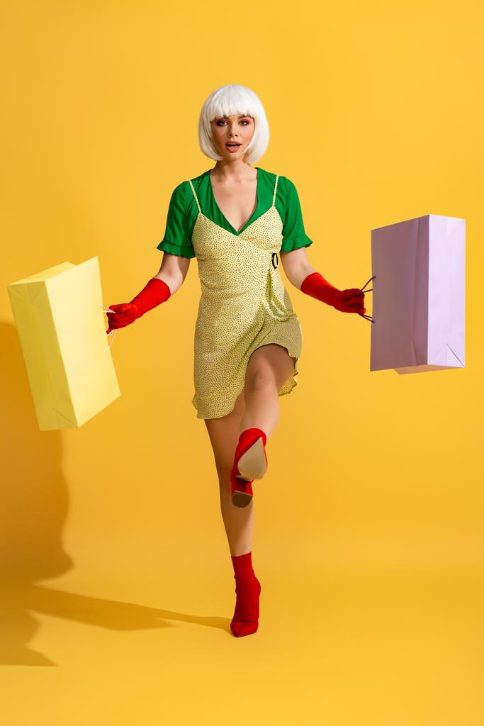 surprise pop art fille en perruque blanche marchant avec des sacs à provisions, sur jaune
 - Photo, image