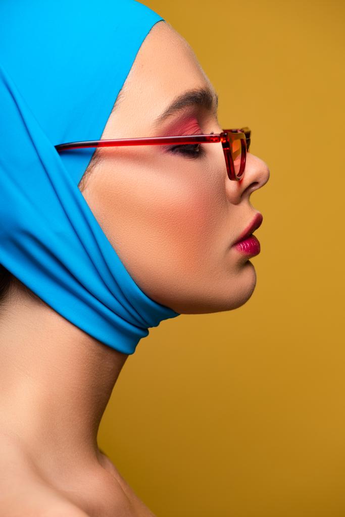 приваблива модна дівчина в модному шарфі і червоних сонцезахисних окулярах, ізольована на жовтому
 - Фото, зображення