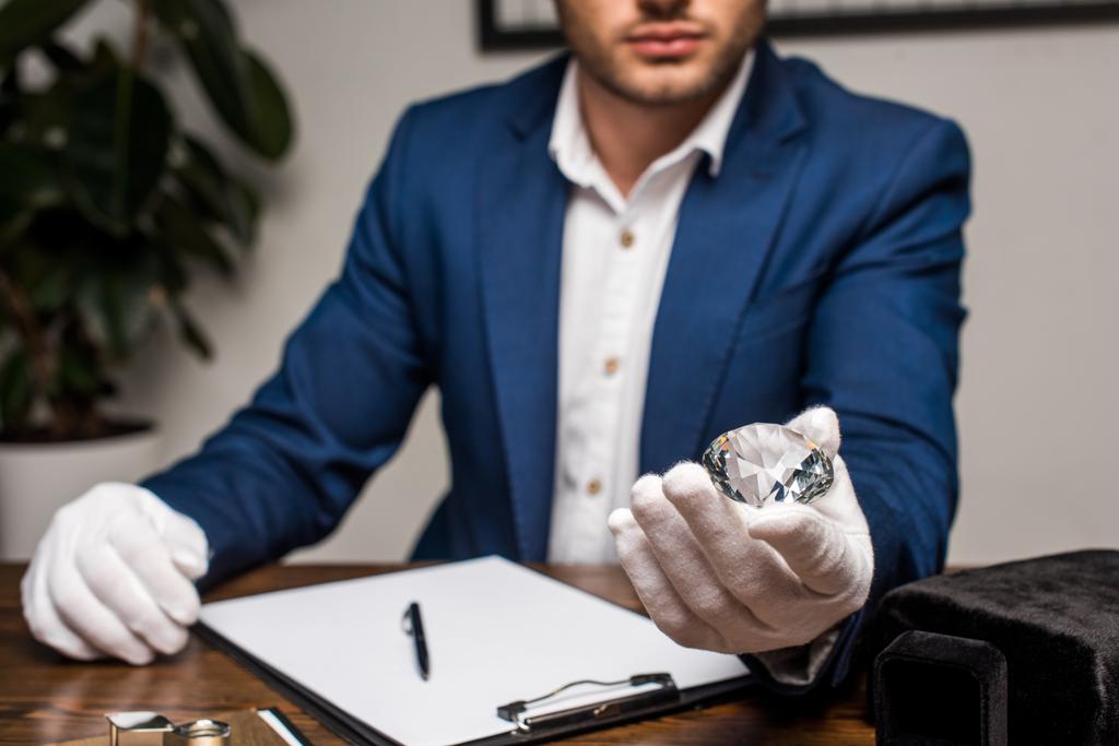 Concentration sélective de l'évaluateur de bijoux tenant la pierre précieuse près du presse-papiers sur la table
 - Photo, image