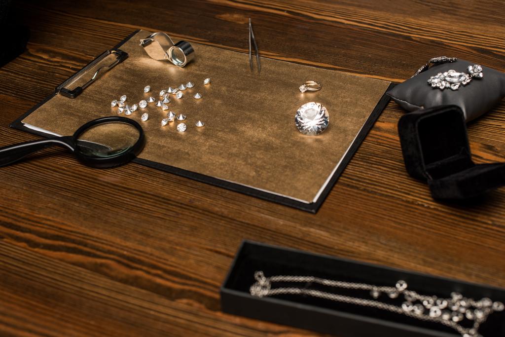 Selektywne skupienie kamieni szlachetnych, biżuterii i szkieł powiększających z pęsetą na pokładzie na drewnianym stole  - Zdjęcie, obraz