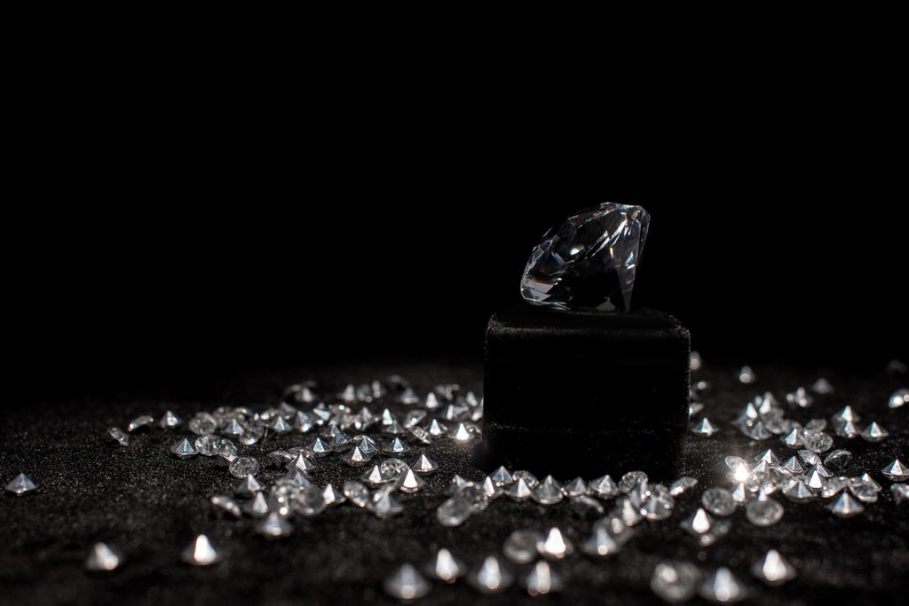 Diamant poblíž drahokamů na černém sametu izolovaném na černém  - Fotografie, Obrázek