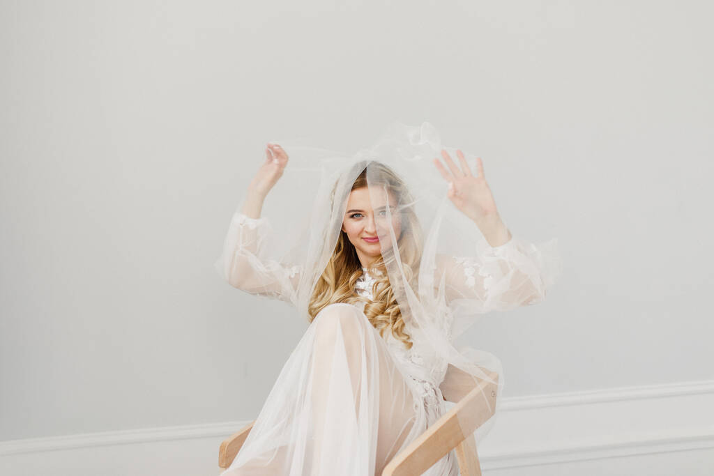portré egy fiatal gyönyörű szőke menyasszony egy csokor egy fehér szobában - Fotó, kép