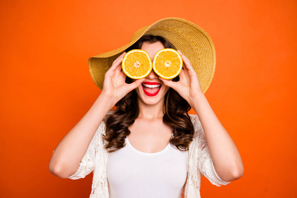 Photo of cheerful positive casual cute nice pretty sweet curly wavy gorgeous girlfriend excited about sights opened when looking through two lemons isolated over vivid orange color background - Foto, Bild