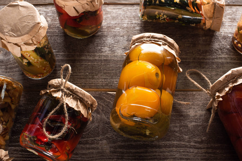 vrchní pohled na domácí chutné okurky ve sklenicích na dřevěném stole - Fotografie, Obrázek