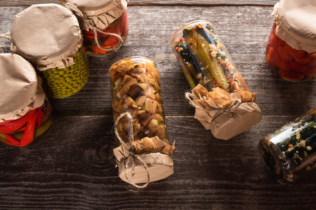 Tahta masadaki kavanozlarda ev yapımı lezzetli turşuların üst görüntüsü - Fotoğraf, Görsel