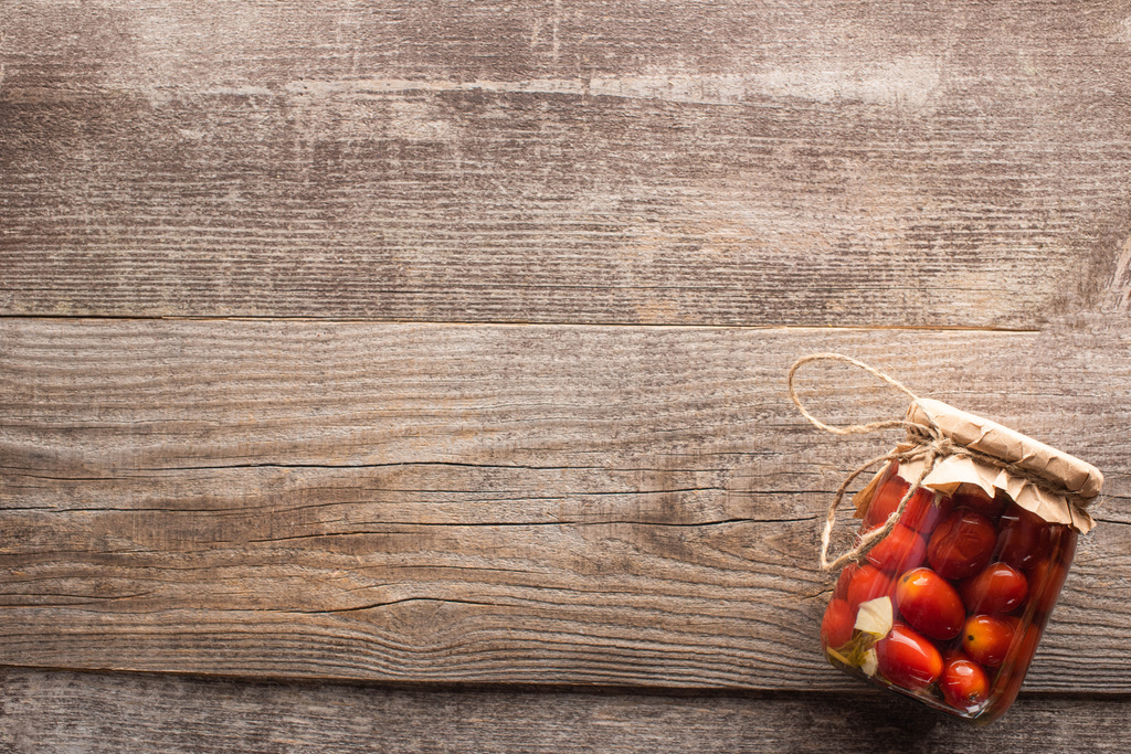 vista superior de rojo casero sabrosos tomates en vinagre en tarro sobre mesa de madera
 - Foto, Imagen