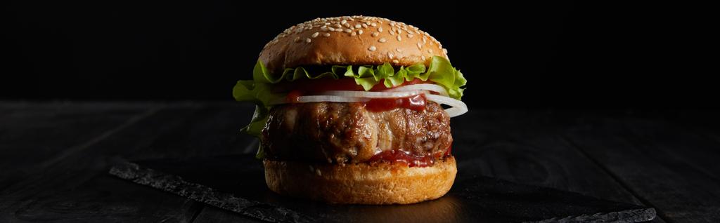 tiro panorâmico de hambúrguer na superfície escura isolada em preto
 - Foto, Imagem