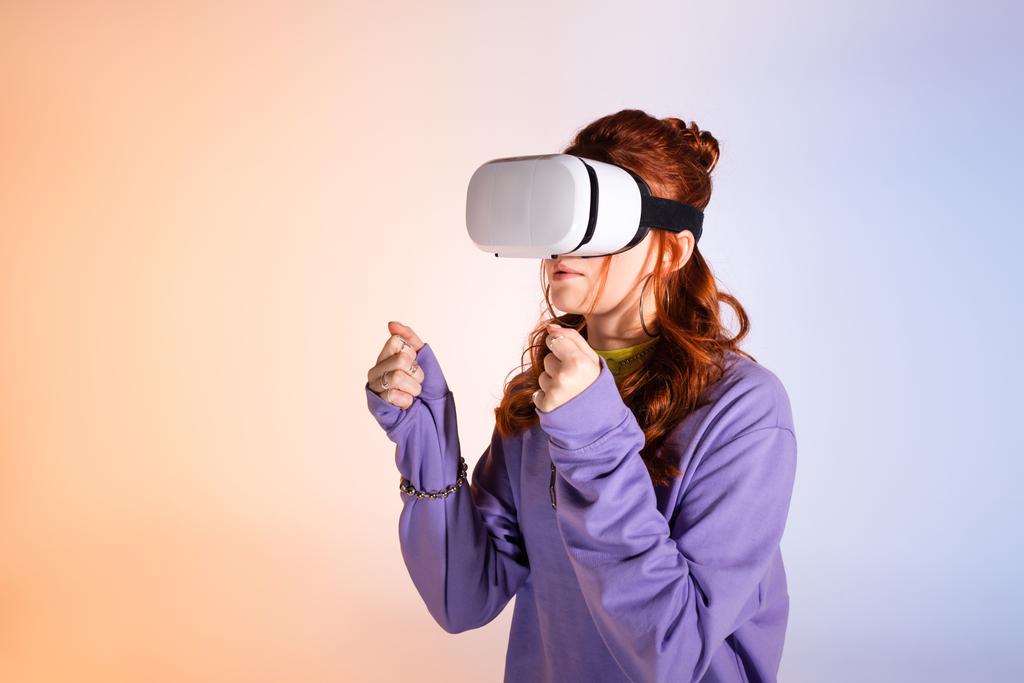 geconcentreerd tiener meisje met behulp van virtual reality headset, op paars en beige  - Foto, afbeelding